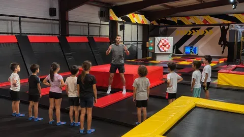 Coach face à un groupe d'enfants alignés sur un trampoline pendant une séance encadrée