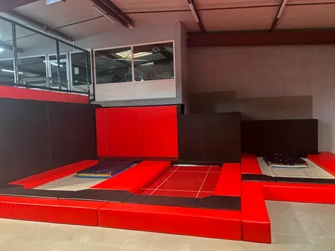 Blocs de mousse rouges et noirs entourant une zone de réception, sous une mezzanine vitrée